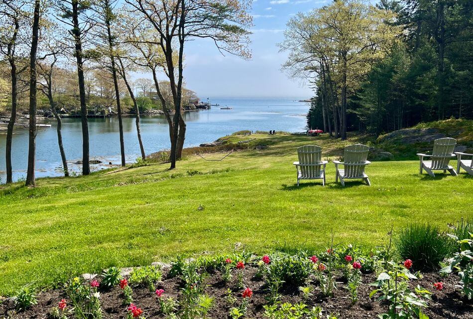 light green adirondack chairs sitting in lawn by garden facing the water